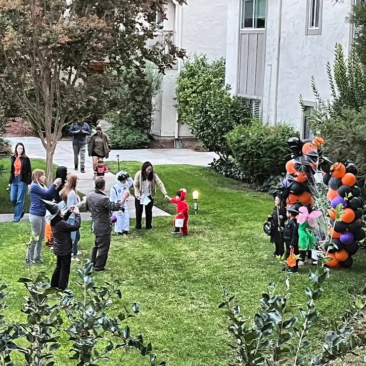 Black, orange and purple Halloween balloon column beside a lawn path during a neighborhood trick-or-treat event