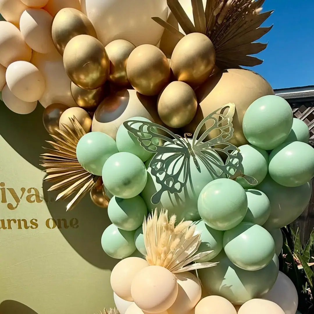 Sage, ivory, and gold first birthday balloon garland with floral accents