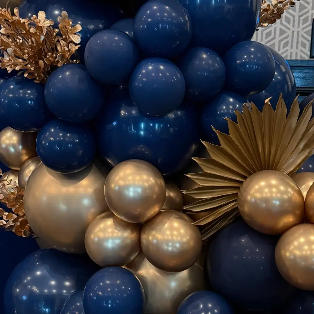 Close-up of a navy and gold chrome balloon garland with gold dried palm and leaf accents