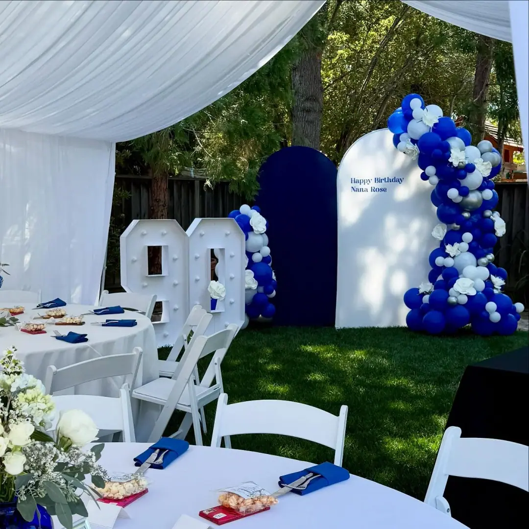 Elegant white, blue, and silver balloon backdrop under restaurant-style chandeliers