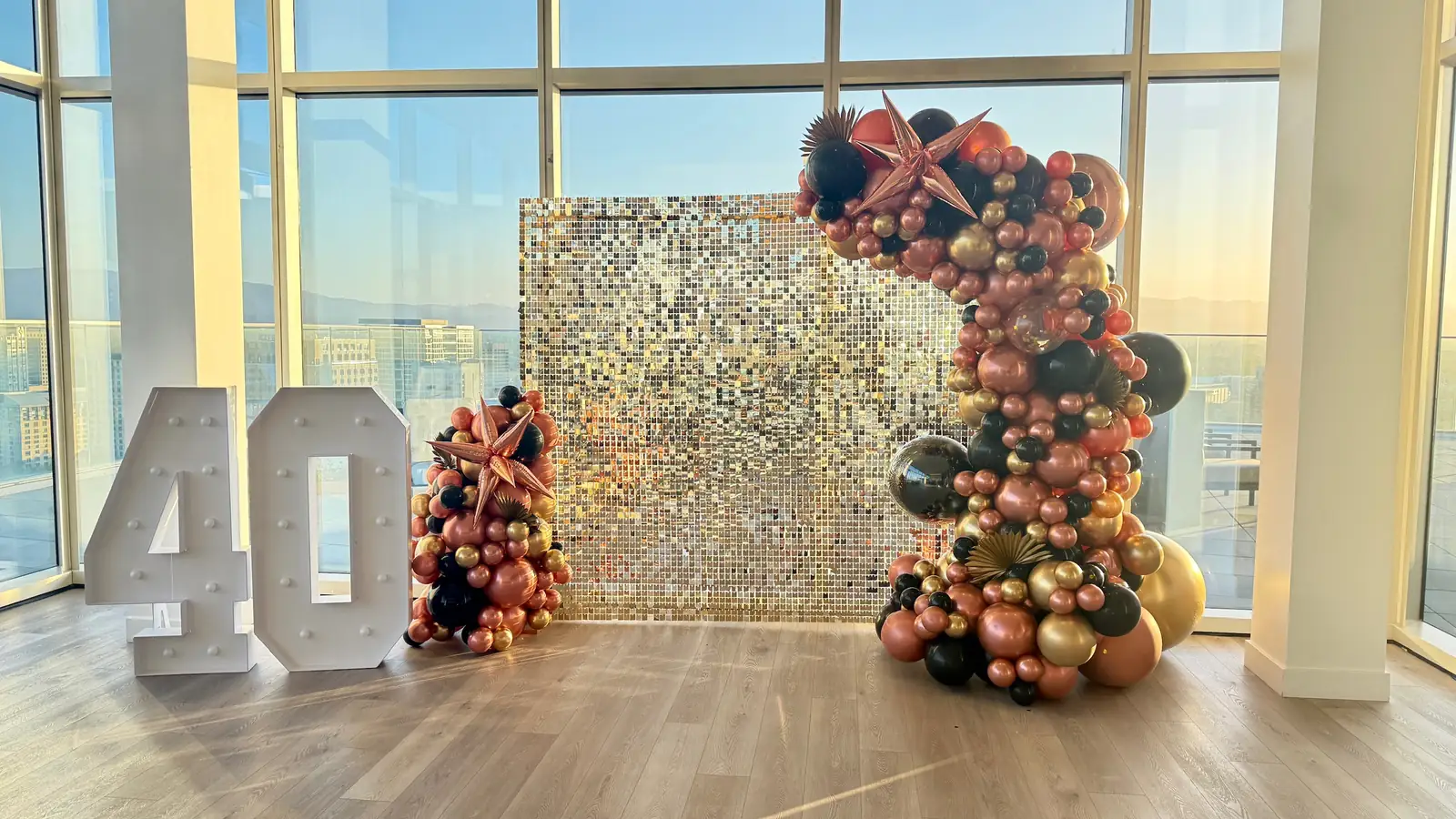 Light-up 40 marquee numbers beside a silver sequin wall and a black, rose gold and copper balloon garland